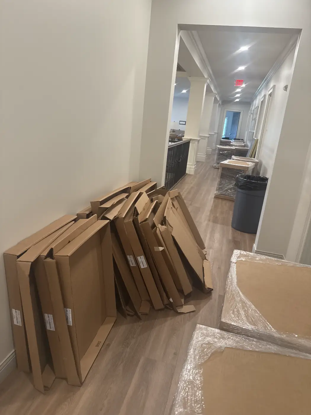 Flattened moving boxes stacked against a hallway wall during an office and property cleanout in Oxford, MS