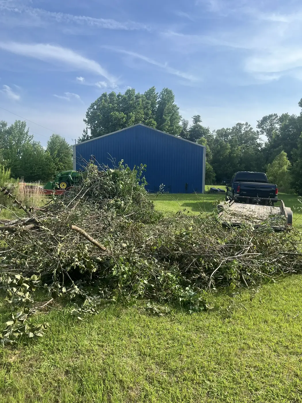 Truck bed and trailer piled with brush, tree branches, and site-clearing debris near Oxford, MS