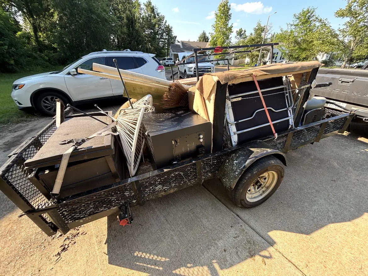 Trailer loaded with patio furniture, a rake, a broom, and a folding table during an Oxford, MS move-out haul
